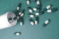 Green and white pills spilling from white bottle Royalty Free Stock Photo