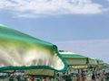 Green and white striped beach umbrella across other umbrellas and blue sky. Beach resort complex. Summer concept. Copy space Royalty Free Stock Photo