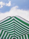 Green and white striped beach umbrella against sky with white cloud Royalty Free Stock Photo