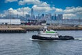 Green and White Tug Boat with New York in Background