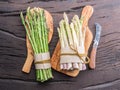 Green and white types of asparagus sprouts on wooden table. Top view