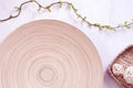 Green willow leaves on branch, decorative balls in a basket and wooden plate.