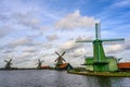 Green windmills and grasslands along the canal on a clear day. Beautiful clouds in Zaanse Schans