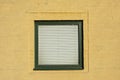 Green window with blinds on yellow plastered old wall Royalty Free Stock Photo