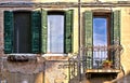 Green windows and balcony with old building facade and brick texture in Venice, Italy