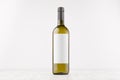 Green wine bottle with blank white label on white wooden board, mock up. Royalty Free Stock Photo