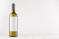 Green wine bottle with blank white label on white wooden board, mock up. Royalty Free Stock Photo