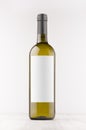 Green wine bottle with blank white label on white wooden board, mock up, vertical. Royalty Free Stock Photo