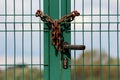 Green wire fence doors with metal frame and black door handle connected with rusted chain and locked with padlock Royalty Free Stock Photo