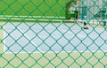 Green Wire Fence with Tennis Court Background