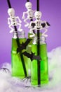Green witch drink in glass bottles with spooky skeleton cocktail straws and with black bats, Halloween funny food idea, bright