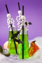 Green witch drink in glass bottles with spooky skeleton cocktail straws and with black bats, Halloween funny food idea, bright