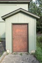 A green wood toolshed with a copper door