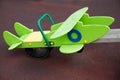 A green wooden airplane mounted on a swing on a clear sunny day. Playgrounds, sports