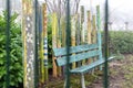 Green wooden bench behind fence with colourful wooden poles in park Royalty Free Stock Photo