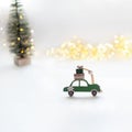 green wooden car with New Year's gifts on the roof on a white background. Christmas tree and bokeh lights in the background. Royalty Free Stock Photo