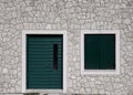 green wooden door with shutters closed on window against stone wall on house Royalty Free Stock Photo