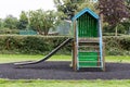 Green wooden house with slider on empty playground Royalty Free Stock Photo