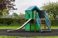 Green wooden house with slider on empty playground Royalty Free Stock Photo