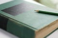 A green wooden pencil is placed on the hardback or textbook. Royalty Free Stock Photo