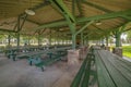 Green wooden picnic tables and benches inside the pavilion of a park Royalty Free Stock Photo