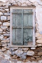 Green wooden shabby window, aged stonewall background, front view. Greek Island, Greece