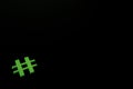 Green wooden symbol Hashtag `#` on blsck background