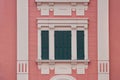 Green wooden window with shutters in white frame on pink wall Royalty Free Stock Photo