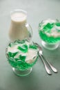 Green woodruff Jell-O and vanilla sauce in glass bowl