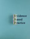 Green words EBP Evidence-based practice concept on wooden cubes. Beautiful blue background.