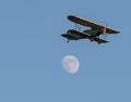 Green antique bi plane with yellow trim flying past full moon Royalty Free Stock Photo