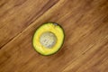 Green yellow avocado half on wooden table. Single avocado top view photo. Cut avocado vegetable on wooden board.