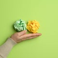 Green and yellow crumpled ball of paper in a female hand Royalty Free Stock Photo