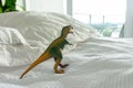 Green and yellow plastic dinosaur toy on bed