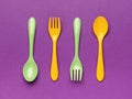 Green and yellow plastic spoons on a purple background. Minimal concept of plastic tableware Royalty Free Stock Photo