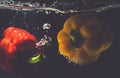 Green Yellow Red bell peppers drop into the water with splash. Royalty Free Stock Photo