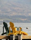 Two wooden armchairs on a pier facing Okanagan Lake.