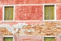 Green-yellow wooden windows with peeling paint on an old, red wall of the house. Royalty Free Stock Photo