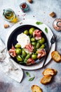 Green zebra tomatoes and sliced burrata cheese salad with fresh arugula, prosciutto or jamon, olives and toasted bread. Royalty Free Stock Photo