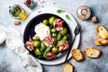 Green zebra tomatoes and sliced burrata cheese salad with fresh arugula, prosciutto or jamon, olives and toasted bread. Royalty Free Stock Photo