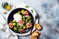 Green zebra tomatoes and sliced burrata cheese salad with fresh arugula, prosciutto or jamon, olives and toasted bread. Royalty Free Stock Photo