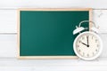 Greenboard with alarm clock on white wood background , empty board ,  time management and education concept Royalty Free Stock Photo