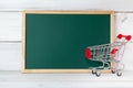 Greenboard with trolley shopping cart on white wood background , empty board ,  marketing and  education concept Royalty Free Stock Photo