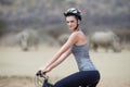 The greenest way to safari. Portrait of a young woman on a bicycle looking at a group of rhinos in the veld.