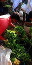 A greengrocer giving coriander to the customer at street