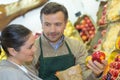 Greengrocer serving apple to customer