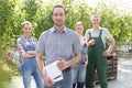 Portrait of confident supervisor and gardeners standing at greenhouse