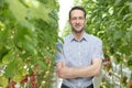 Portrait of confident supervisor standing amidst plants in greenhouse