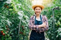 Portrait of a farm owner with crossed arms amid ripe green tomatoes