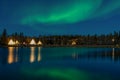 Greenish Aurora Borealis over illuminated Tipi near a lake, Yellow knife village